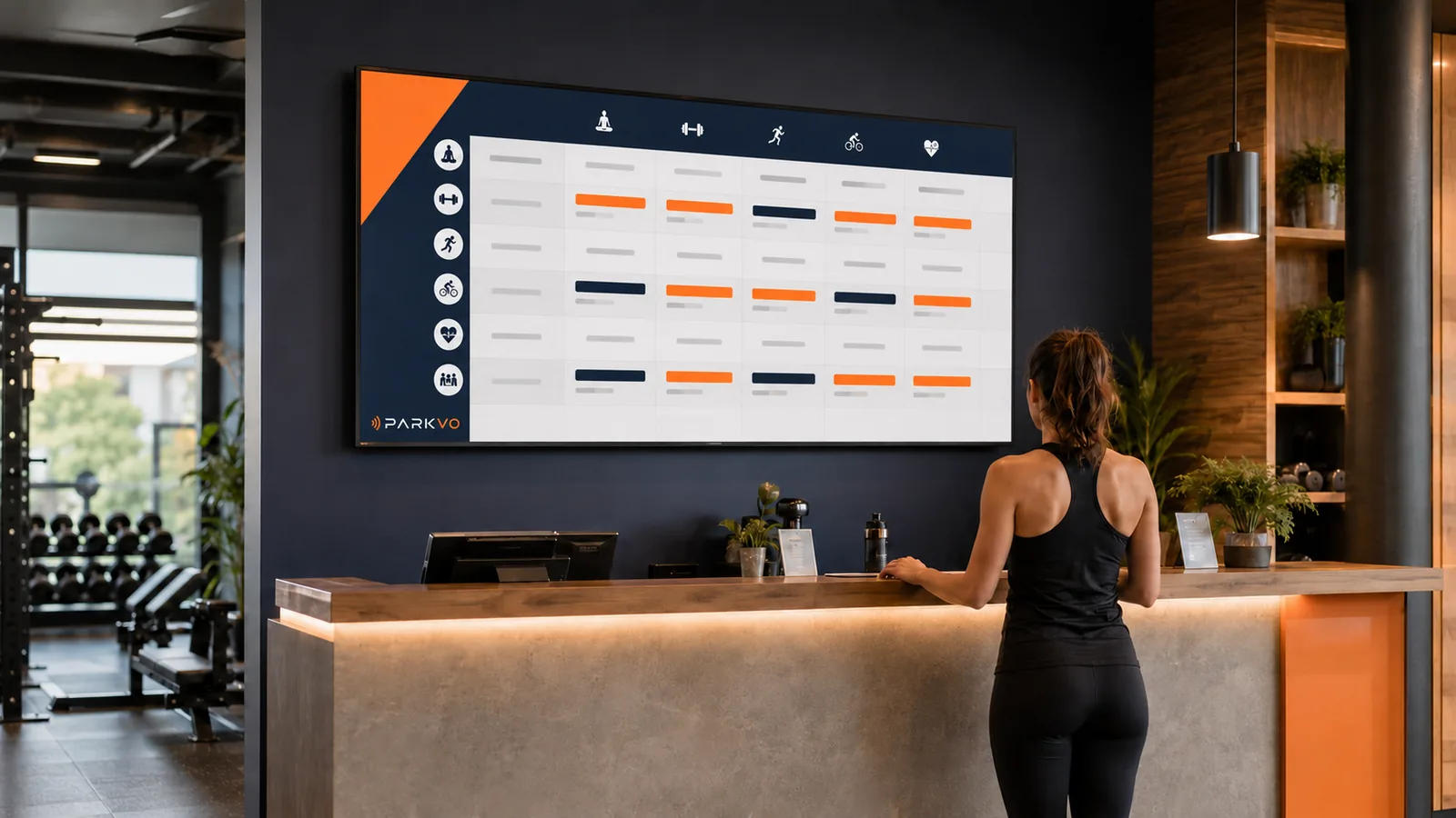 Großes Display am Empfang eines Fitnessstudios mit dem Kursplan der Woche.